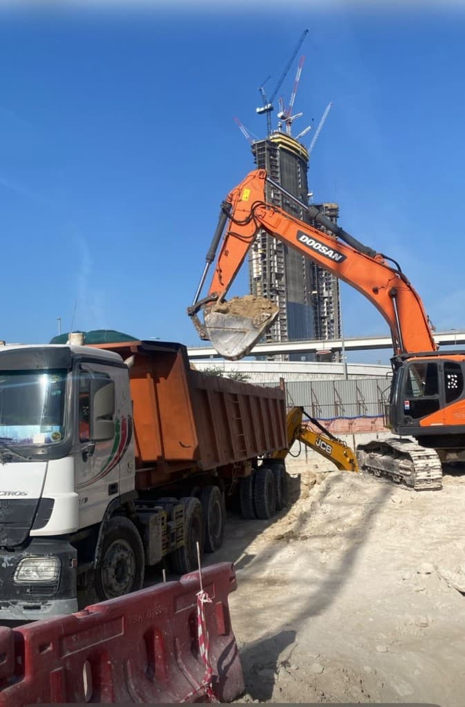 Doosan excavator loading a Mercedes dump truck with sand during backfilling works