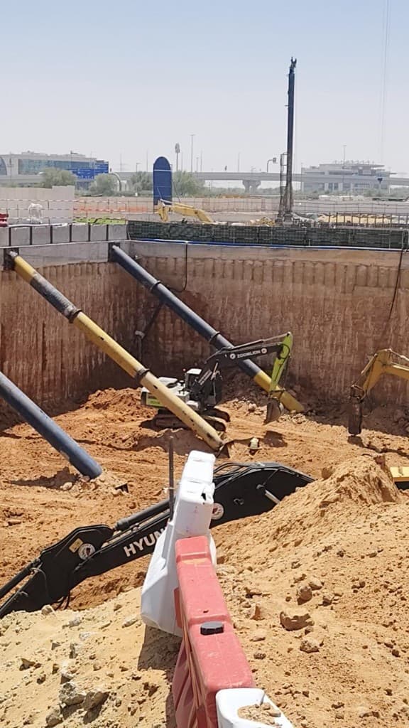 Deep foundation excavation with steel bracing and excavators on a Dubai site