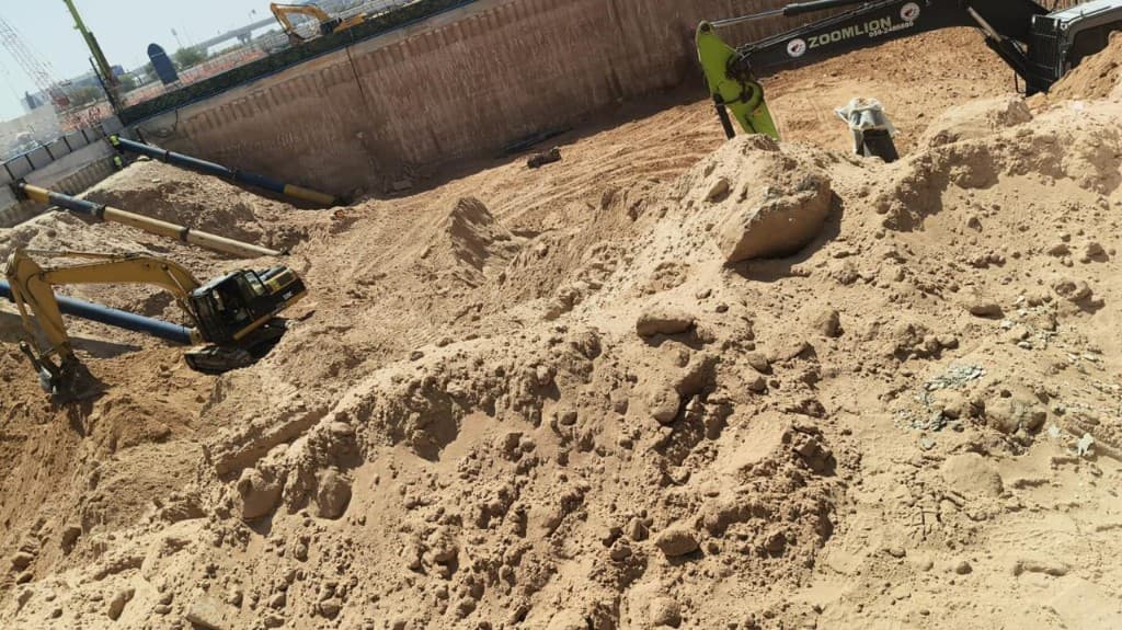 Excavation pit with blue steel rakers and heavy equipment on site